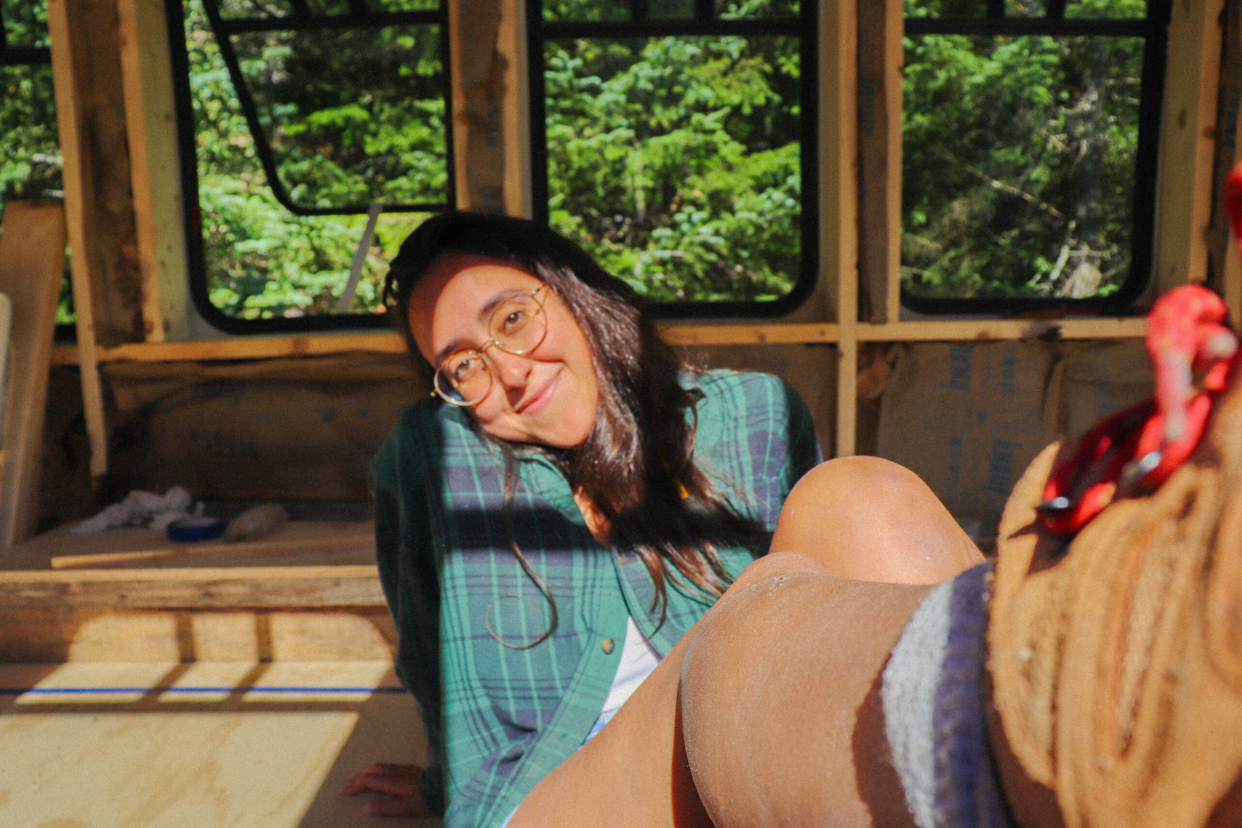 girl sitting on the floor with a leg up, windows behind her.