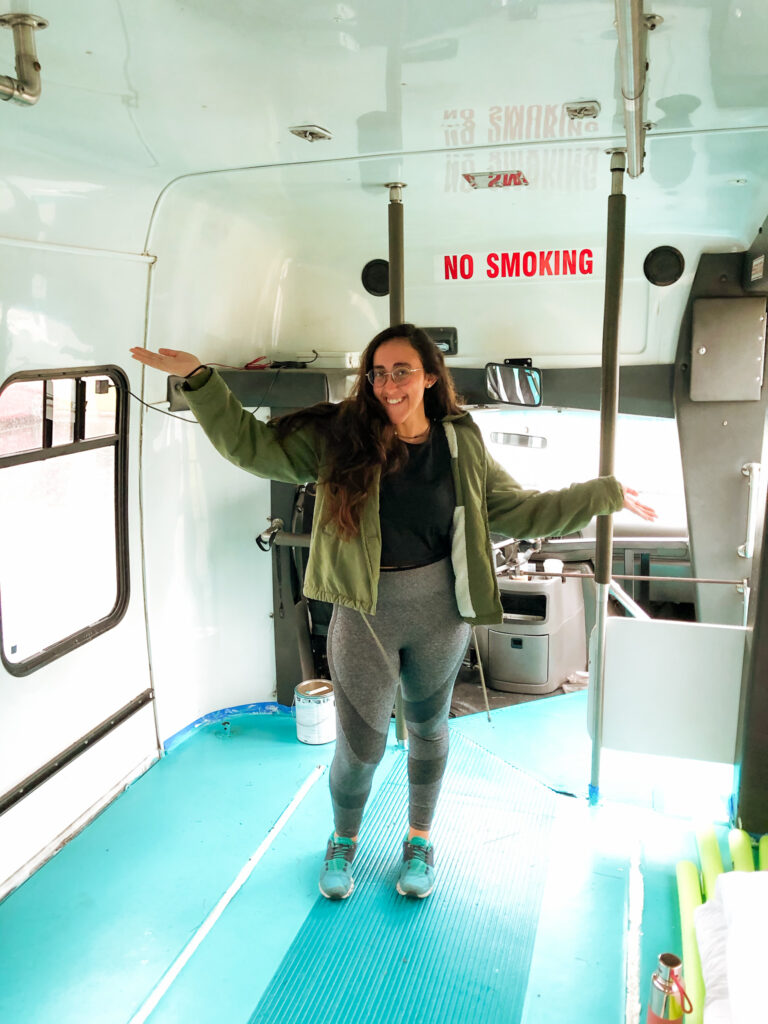 girl smiling with her arms out in a shuttle bus with a teal floor