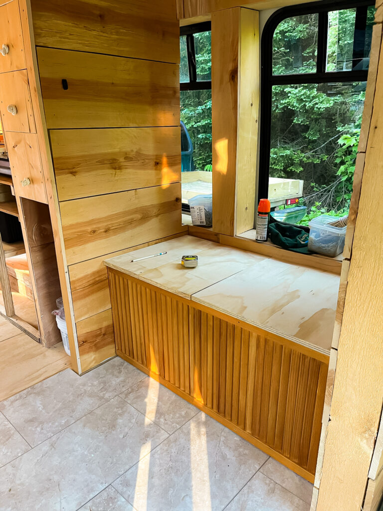 a wooden bench with a window above it.