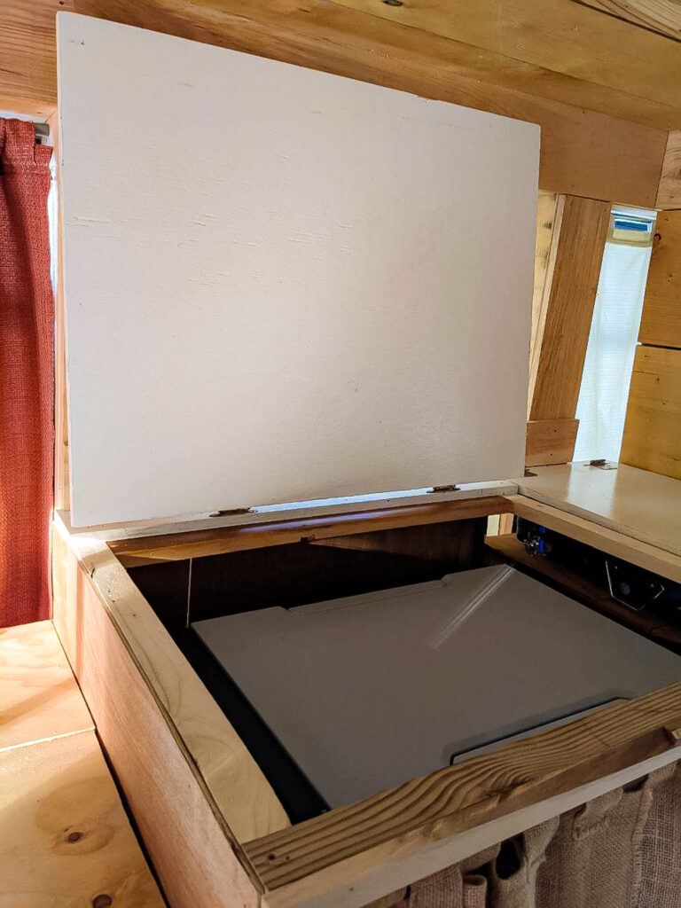 a counter hinged open to reveal a electric refrigerator.