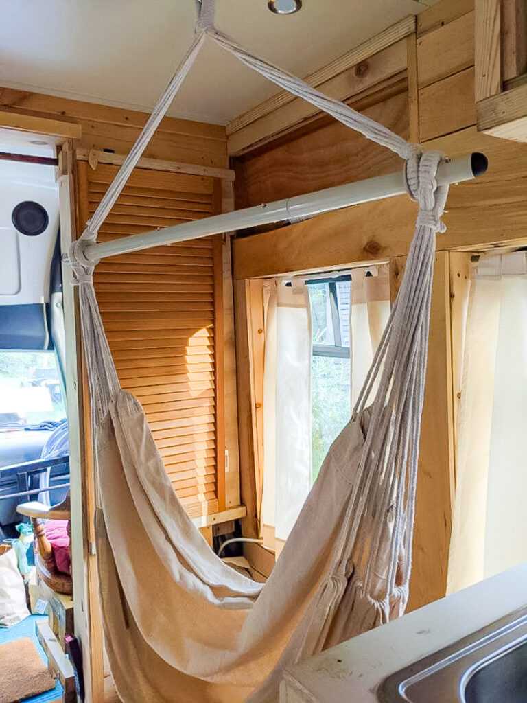 a hammock chair in a wooden room with windows.